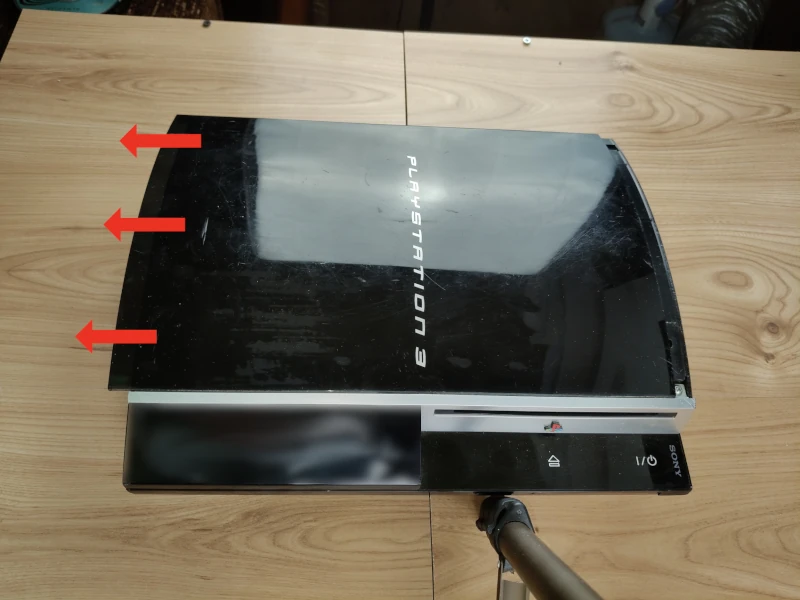 Panel przedni konsoli PlayStation FAT 3 - strzałki z kierunkiem zdejmowania